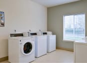 Thumbnail 9 of 50 - a laundry room with four washing machines and a window at Quail Run Apartments, Vancouver