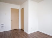 Thumbnail 25 of 50 - an empty room with white walls and wooden floors and two doors at Quail Run Apartments, Vancouver, Washington