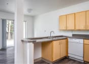 Thumbnail 28 of 50 - an empty kitchen with wooden cabinets and a sink at Quail Run Apartments, Vancouver, WA 98684
