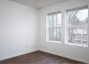 Thumbnail 34 of 50 - an empty room with two windows and a wooden floor at Quail Run Apartments, Vancouver, 98684