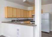 Thumbnail 39 of 50 - a kitchen with a counter and a refrigerator at Quail Run Apartments, WA