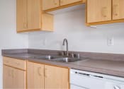 Thumbnail 42 of 50 - a kitchen with wooden cabinets and a sink at Quail Run Apartments, Vancouver, WA