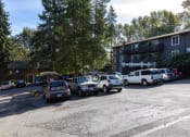 Thumbnail 21 of 49 - a parking lot filled with cars in front of a building at Whisperwood, Seattle, WA 98168