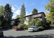 Thumbnail 27 of 49 - an apartment building with cars parked in a parking lot at Whisperwood, Seattle, 98168