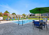 Thumbnail 5 of 63 - A green umbrella is on a table next to a pool at The Henley Apartments, California, 94585