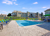 Thumbnail 4 of 63 - A swimming pool surrounded by chairs and a building in the background at The Henley Apartments, Suisun City, CA