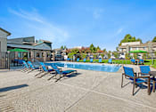 Thumbnail 3 of 63 - A pool area with sun loungers and a building in the background at The Henley Apartments, Suisun City, CA