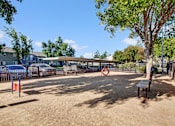 Thumbnail 14 of 63 - A playground with a red and white sign, a bench, and a tree at The Henley Apartments, Suisun City, 94585