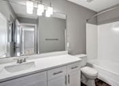 Thumbnail 49 of 63 - A white bathroom with a sink, mirror, toilet and bathtub at The Henley Apartments, Suisun City