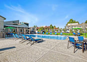 Thumbnail 8 of 63 - A pool area with sun loungers and a building in the background at The Henley Apartments, California