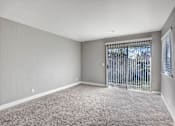Thumbnail 41 of 63 - A room with a carpeted floor and a window with a metal gate at The Henley Apartments, Suisun City, CA