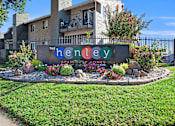 Thumbnail 55 of 63 - A sign for The Henley Apartments is surrounded by flowers and rocks at The Henley Apartments, Suisun City, CA, 94585
