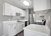 Thumbnail 23 of 63 - A kitchen with white cabinets and a stainless steel refrigerator at The Henley Apartments, Suisun City, CA