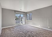 Thumbnail 44 of 63 - A room with a carpeted floor and a sliding glass door leading outside at The Henley Apartments, California