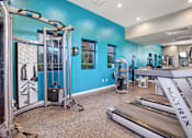 Thumbnail 12 of 63 - A gym with blue walls and a variety of equipment at The Henley Apartments, Suisun City, 94585