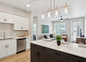 Thumbnail 22 of 32 - A modern kitchen with a large island and a dining area at Ironwood Ranch Apartments,Maricopa