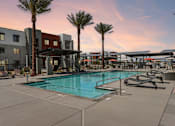 Thumbnail 11 of 32 - A swimming pool surrounded by palm trees and lounge chairs at Ironwood Ranch Apartments,Maricopa,Arizona
