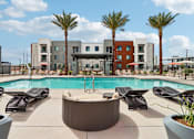 Thumbnail 9 of 32 - A pool surrounded by lounge chairs and palm trees at Ironwood Ranch Apartments,Arizona