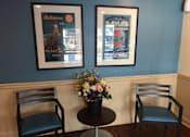 Thumbnail 6 of 10 - Two framed posters on a wall above a table with two chairs at Tabco Towers Apartments, Towson, MD
