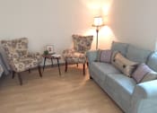 Thumbnail 3 of 10 - A living room with a grey couch, two chairs and a small table at Tabco Towers Apartments, Maryland