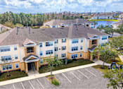 Thumbnail 15 of 24 - A large apartment complex with a parking lot in front at The Villages on Millenia Apartments, Florida, 32839