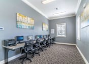 Thumbnail 8 of 24 - A room with grey walls and a carpeted floor has a row of chairs and desks with computers on them at The Villages on Millenia Apartments, Orlando