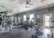 Thumbnail 9 of 24 - A gym with a variety of exercise equipment including treadmills, stationary bikes, and weight machines at The Villages on Millenia Apartments, Orlando, Florida