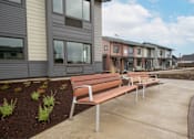 Thumbnail 5 of 29 - Row of benches at Bridge Meadows Redmond Apartments, Redmond, Oregon
