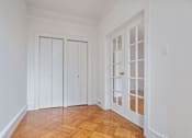 Thumbnail 10 of 17 - A room with white walls and a wooden floor with two white doors.
