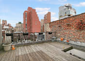 Thumbnail 15 of 17 - A wooden deck with a red building in the background.