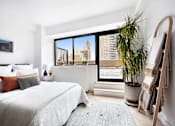 Thumbnail 11 of 56 - A bedroom with a large bed and a view of the city.