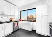 Thumbnail 21 of 56 - A modern kitchen with white cabinets and a view of the city.