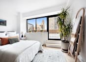 Thumbnail 36 of 56 - A bedroom with a large bed and a view of the city.