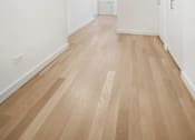 Thumbnail 39 of 56 - A long hallway with wood floors and white walls.