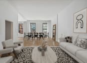 Thumbnail 1 of 9 - A living room with a white couch, a coffee table, and a painting on the wall.
