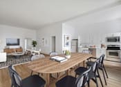 Thumbnail 2 of 9 - A modern dining room with a wooden table and chairs.
