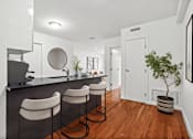 Thumbnail 2 of 11 - A kitchen with white walls and a black counter top with three bar stools.