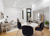 Thumbnail 5 of 18 - A modern dining room with a white table and black chairs.