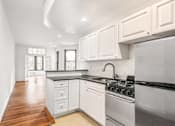Thumbnail 9 of 18 - A kitchen with white cabinets and a black stove top oven.