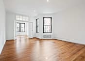 Thumbnail 11 of 18 - A large empty room with wooden floors and white walls.