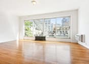 Thumbnail 8 of 18 - A room with wooden floors and a large window overlooking a cityscape.