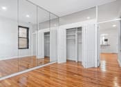 Thumbnail 6 of 18 - A room with a wooden floor and white walls.