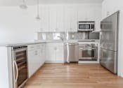 Thumbnail 18 of 19 - A kitchen with stainless steel appliances and wooden floors.