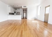 Thumbnail 7 of 19 - A spacious room with wooden flooring and white walls.