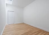 Thumbnail 10 of 18 - A room with a white door and wooden flooring.