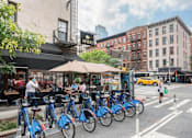 Thumbnail 14 of 18 - A row of blue bikes are parked on the side of a street.