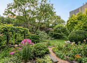 Thumbnail 2 of 18 - A garden with a brick pathway and a variety of plants and flowers.