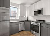 Thumbnail 8 of 18 - A modern kitchen with stainless steel appliances and a window overlooking the city.