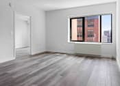Thumbnail 10 of 22 - A room with a large window and a wooden floor.
