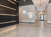 Thumbnail 13 of 22 - A hallway with a wooden floor and a black door on the left.